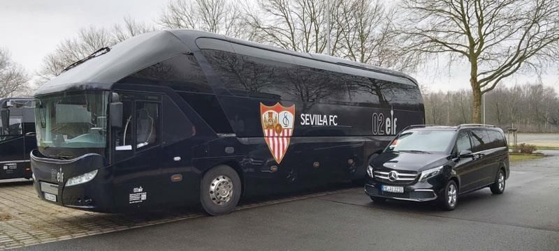Ein schwarzer Bus und ein schwarzer Lieferwagen stehen nebeneinander auf einem Parkplatz.