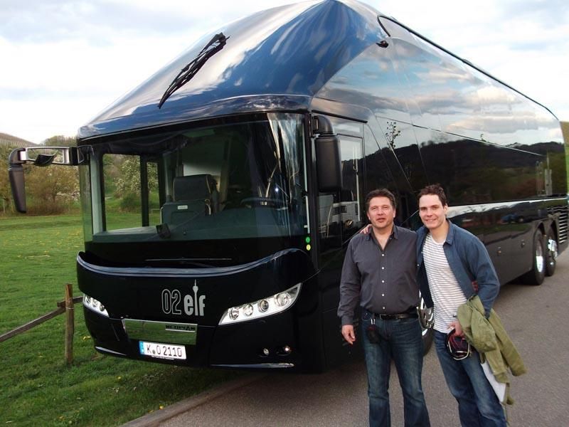 Zwei Männer stehen vor einem Bus mit der Aufschrift „Klein“