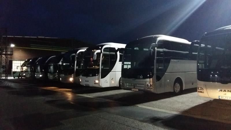 Eine Reihe von Bussen stehen nachts auf einem Parkplatz