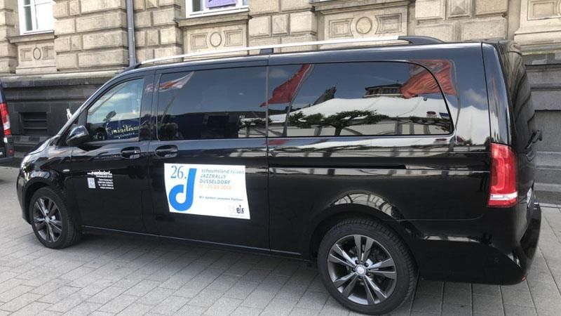 Ein schwarzer Lieferwagen parkt auf dem Bürgersteig vor einem Gebäude.