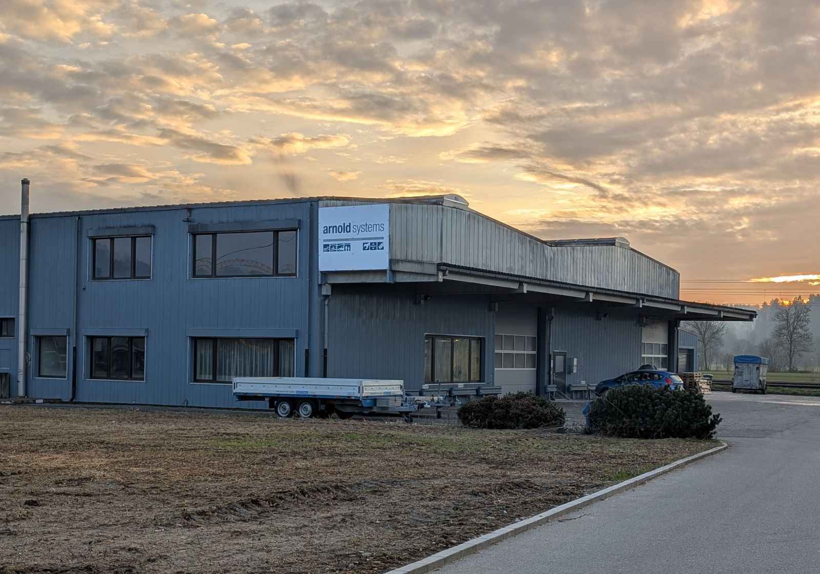 Ein grosses Gebäude mit einem davor geparkten Anhänger bei Sonnenuntergang.