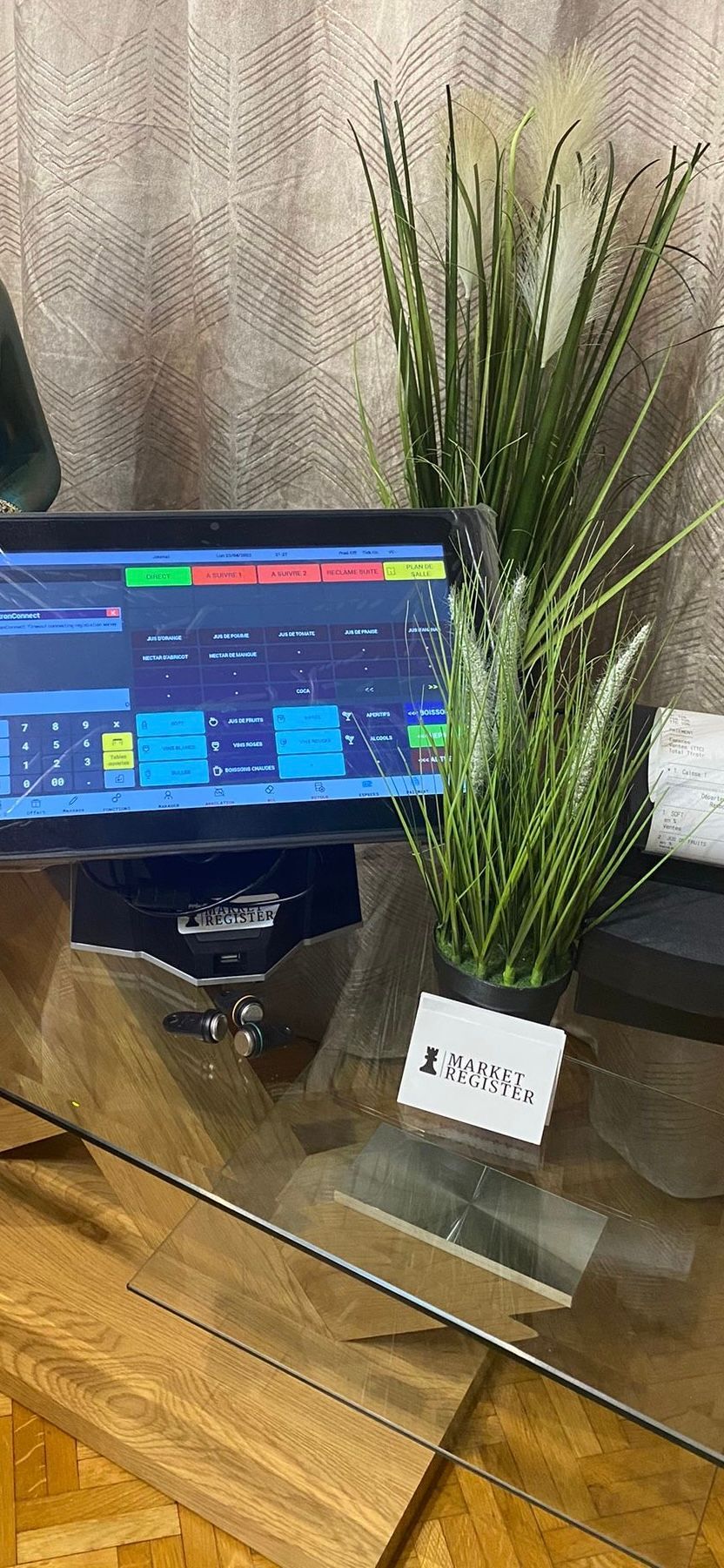 Une plante verte, une crate de visite et une caisse enregistreuse.