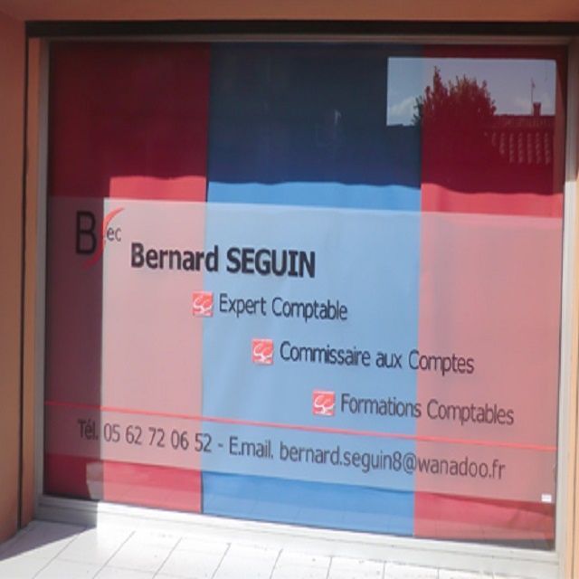 Panneau de Bernard Seguin, comptable. Nom, services et coordonnées sur une fenêtre à panneaux rouges, bleus et blancs.