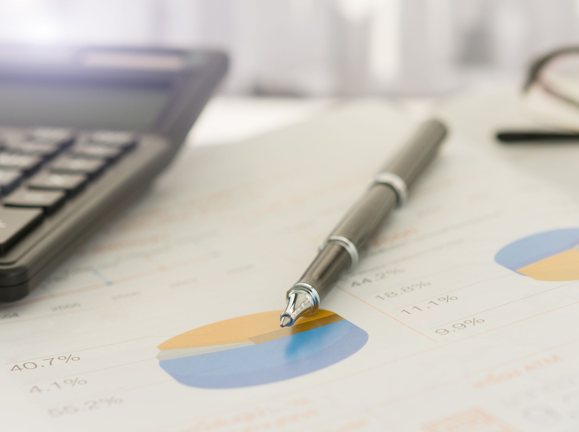 Stylo sur un graphique à secteurs, calculatrice en arrière-plan, impliquant une analyse financière.