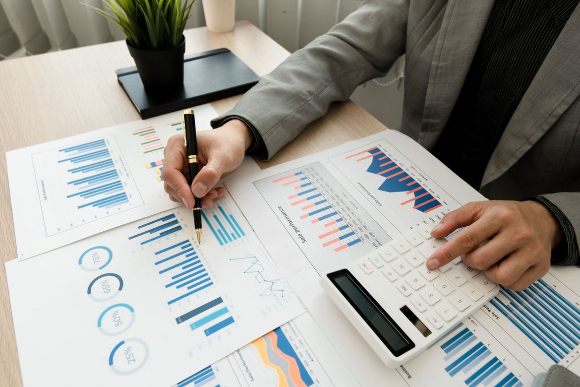 Personne travaillant avec des tableaux, des graphiques et une calculatrice au bureau.