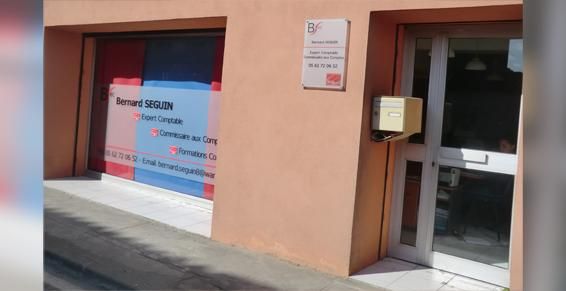 Devanture du bureau ; un panneau au-dessus de la porte et une affiche avec du texte.