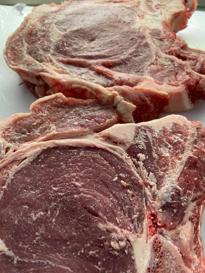 Dos filetes de costilla crudos, cortados de forma gruesa, con marmoleado visible y una gruesa capa de grasa.