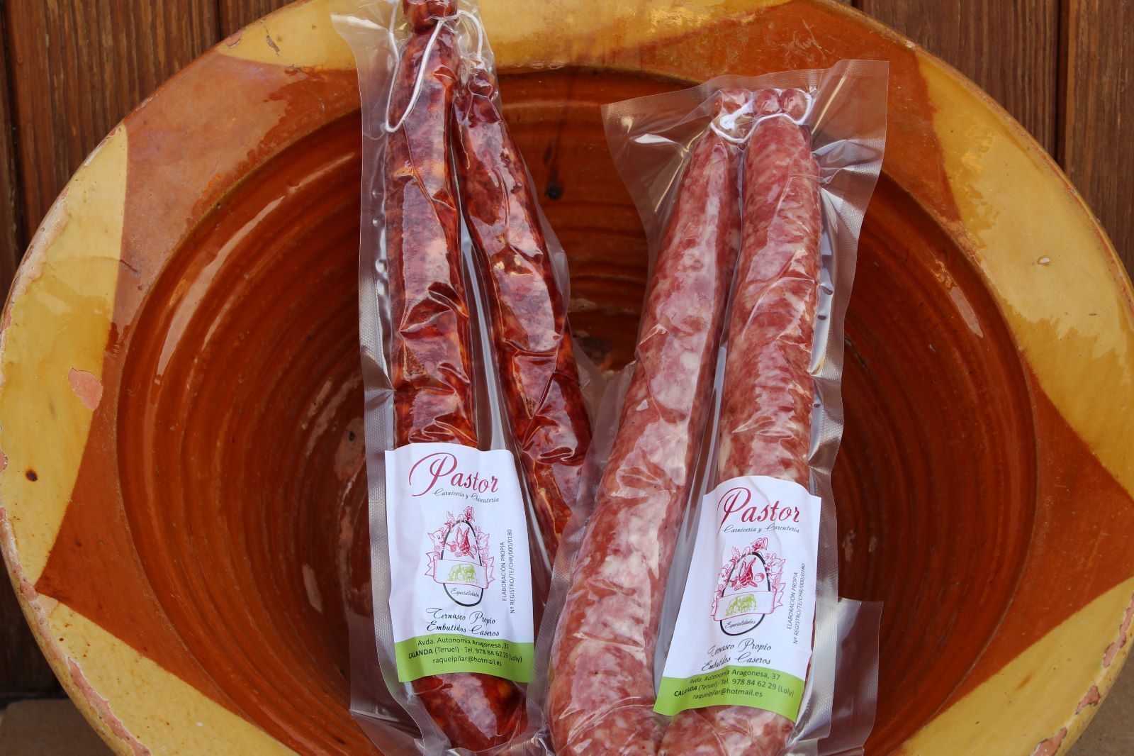 Dos salchichas envasadas, una roja y otra rosa, dentro de un recipiente marrón.