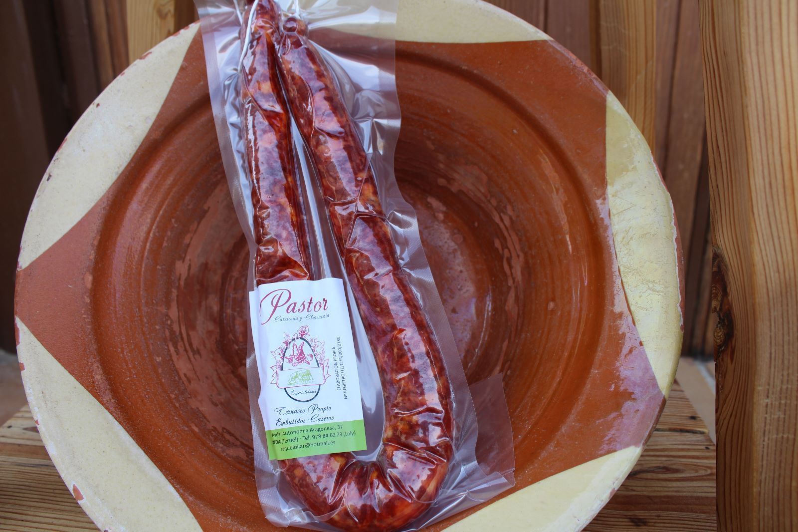 Chorizo en envase transparente dentro de un recipiente marrón y blanco.