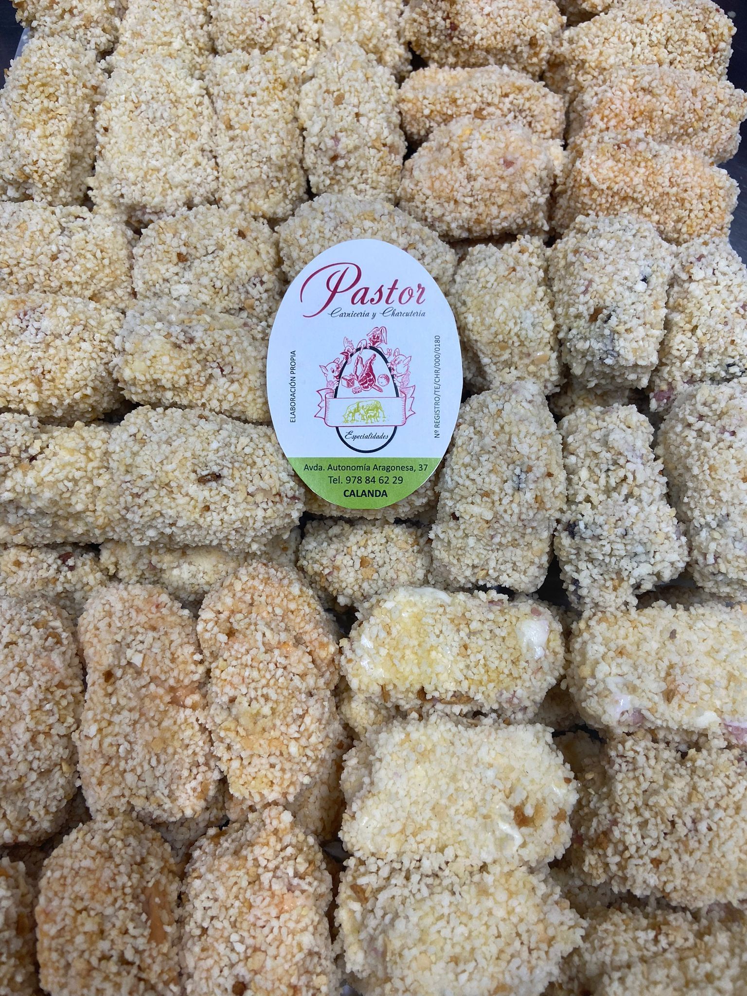 Bandeja de comida empanizada, posiblemente pollo, con una pegatina central que dice