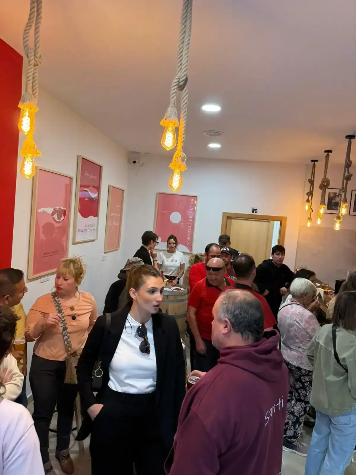 Gente reunida en un interior bien iluminado. Varias personas conversan, otras miran a su alrededor.