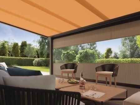 Terrasse mit einziehbarem Sonnenschutz, Gartenmöbeln und Blick auf den Garten.