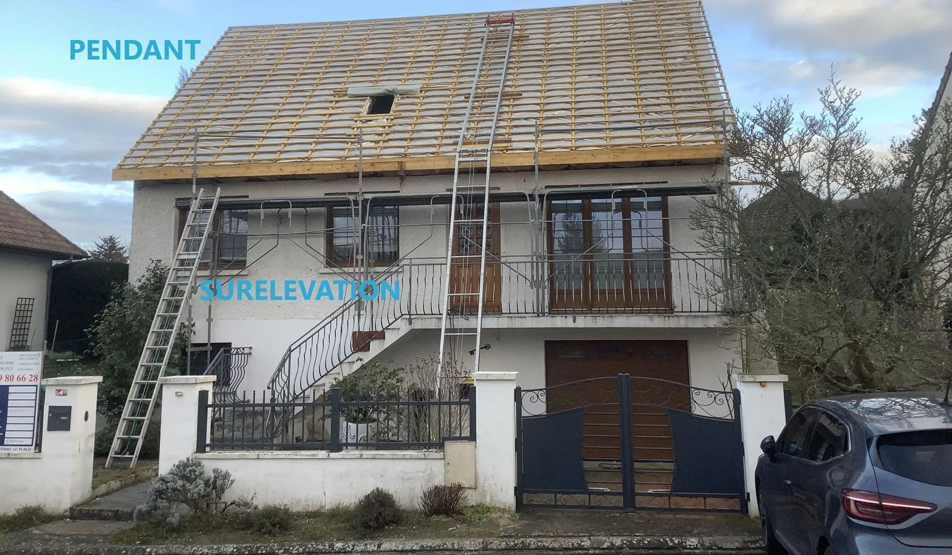 Maison avec toit en construction, deux échelles, portail, voiture et ciel nuageux.