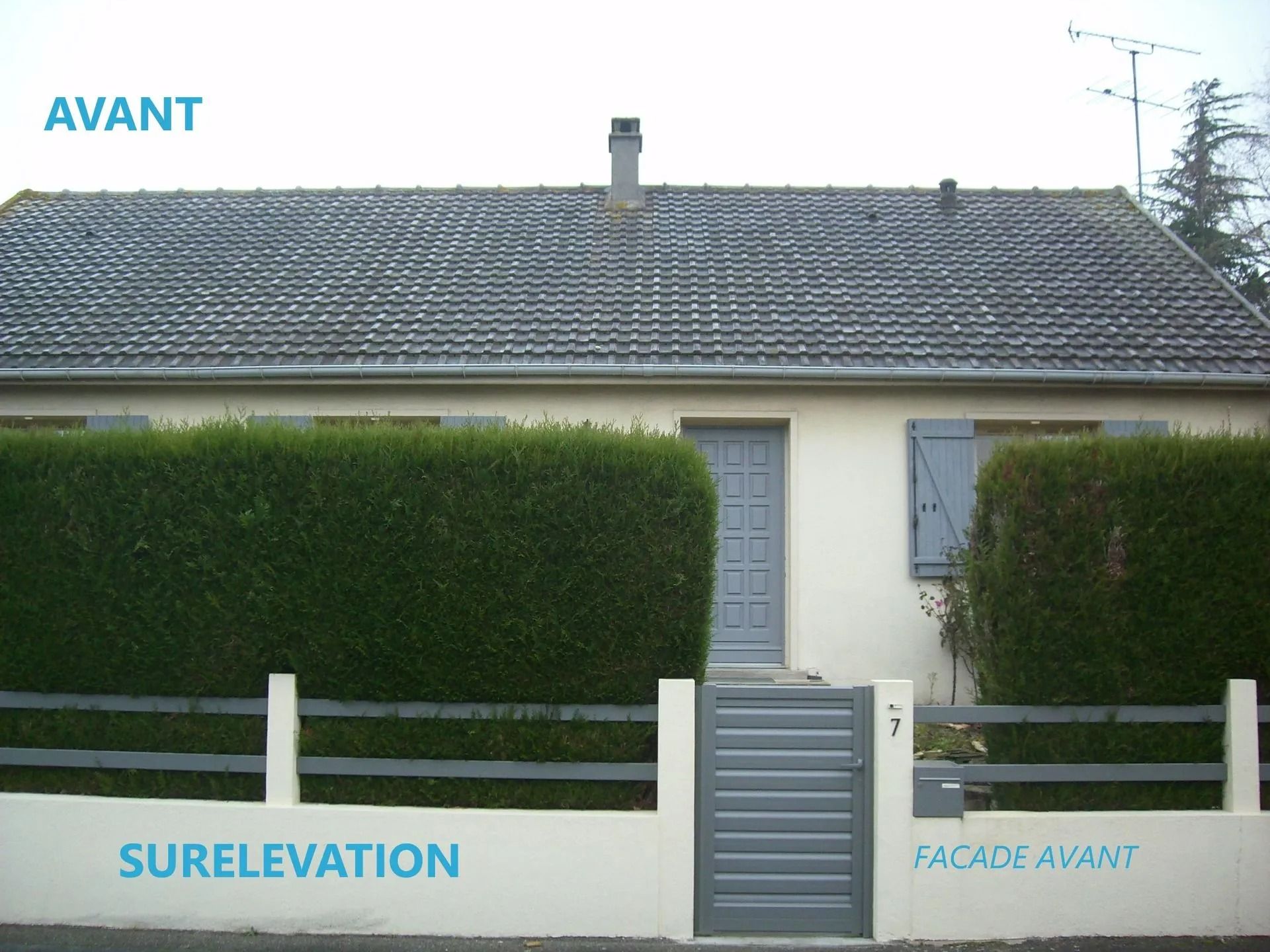 Maison grise avec toit, porte, volets et clôture gris. Haie verte devant. Inscription « AVANT ».