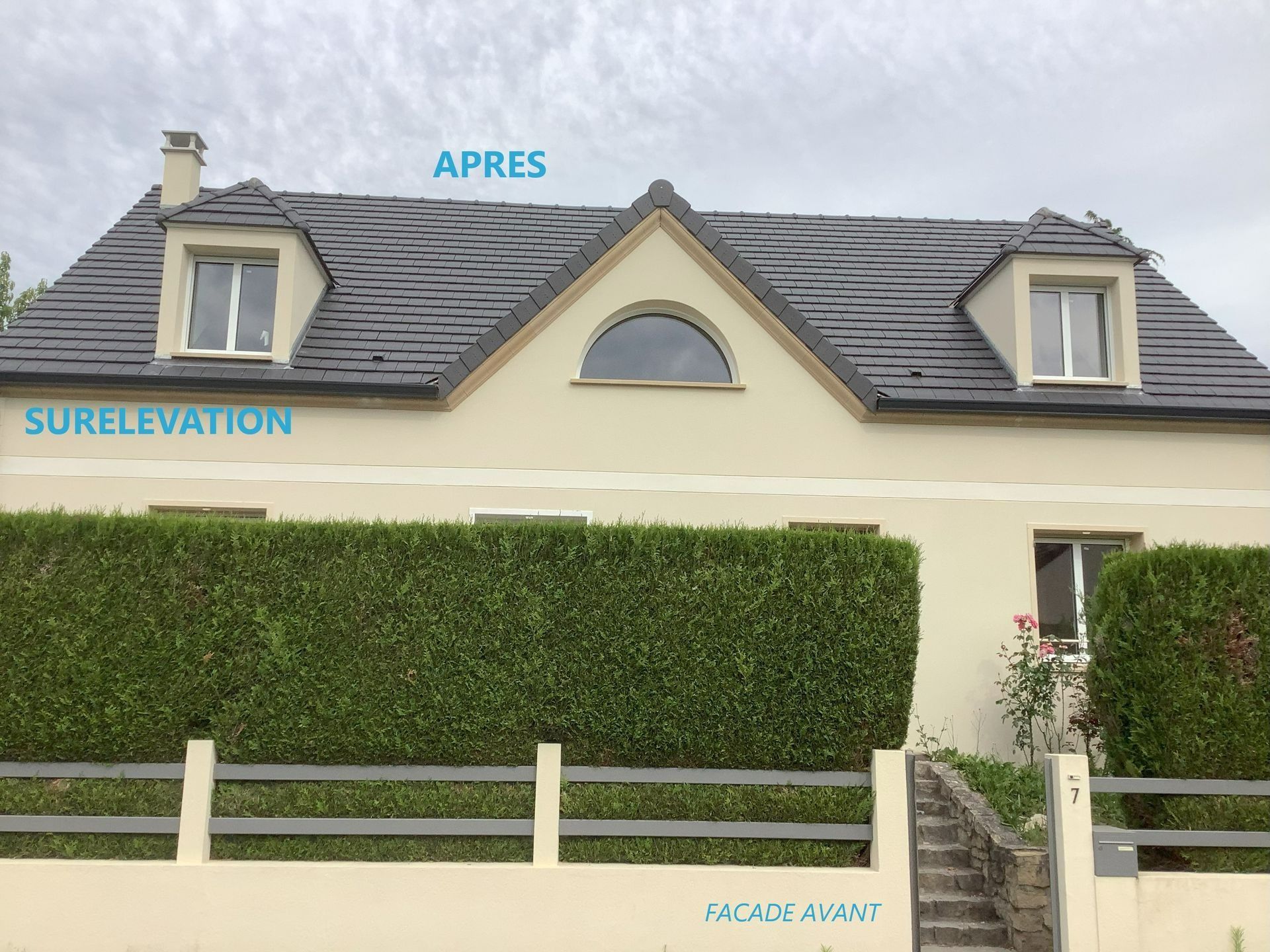 Maison avec une toiture neuve et des lucarnes portant les inscriptions « APRES » et « SURELEVATION », bardage beige, haie verte.