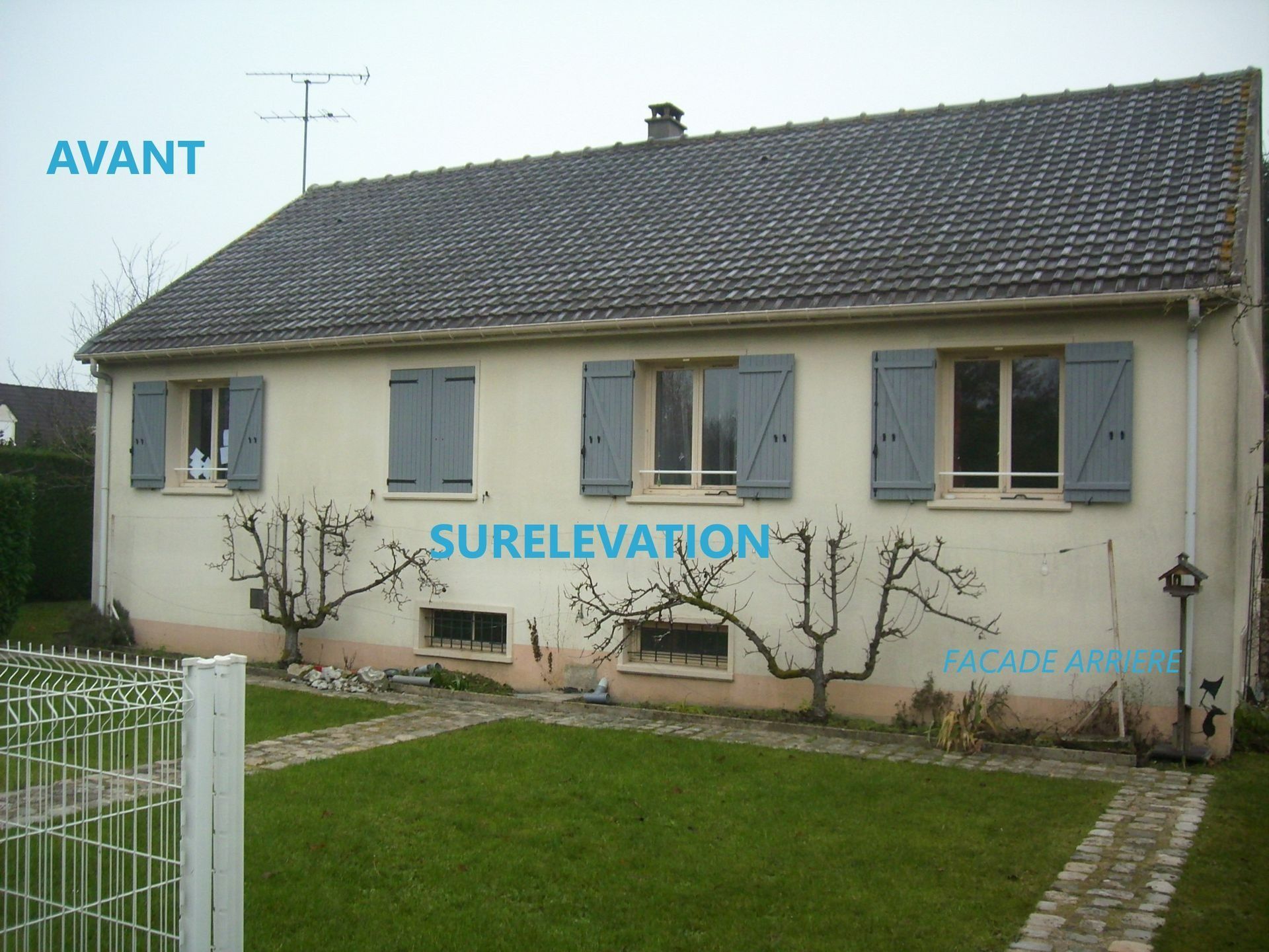 Maison aux volets gris, avant rénovation. Pelouse verte, allée de briques.