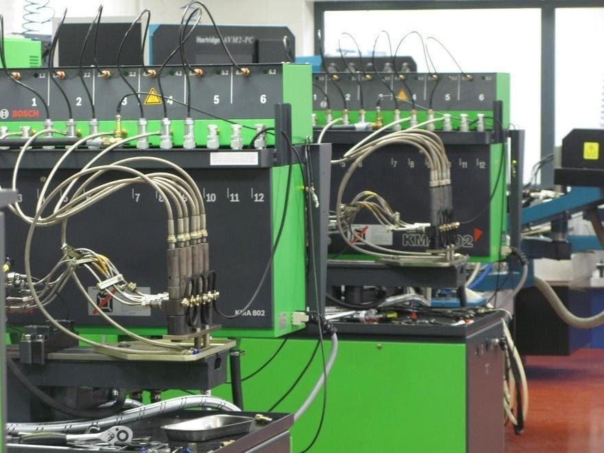 Una fila de máquinas verdes y negras con cables que salen de ellas.