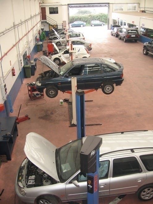 En un garaje se está trabajando en una fila de coches.