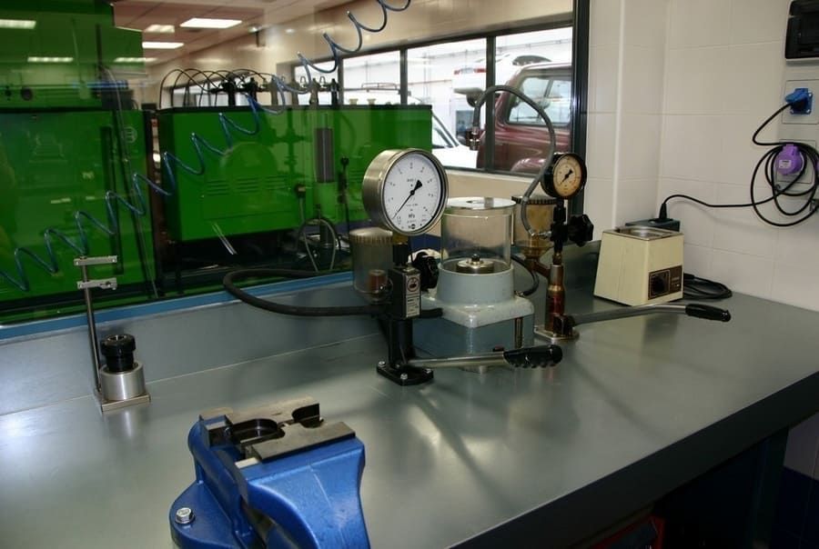 Un banco de trabajo con un tornillo de banco azul y un montón de herramientas sobre él.