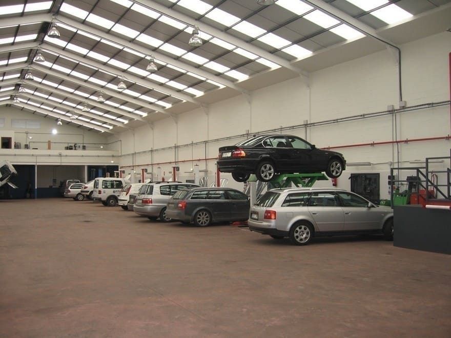 Un coche negro está encima de un coche plateado en un garaje.