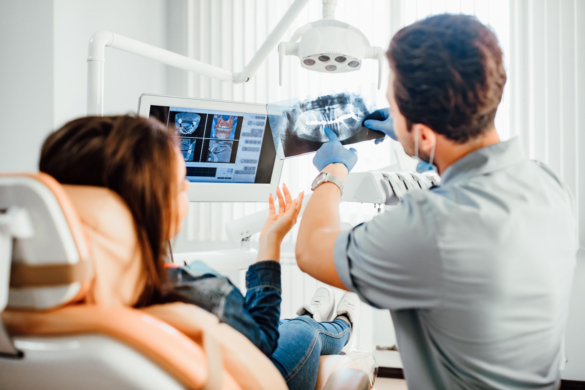 Dentiste qui montre l'analyse d'une radiographie dentaire à une patiente.