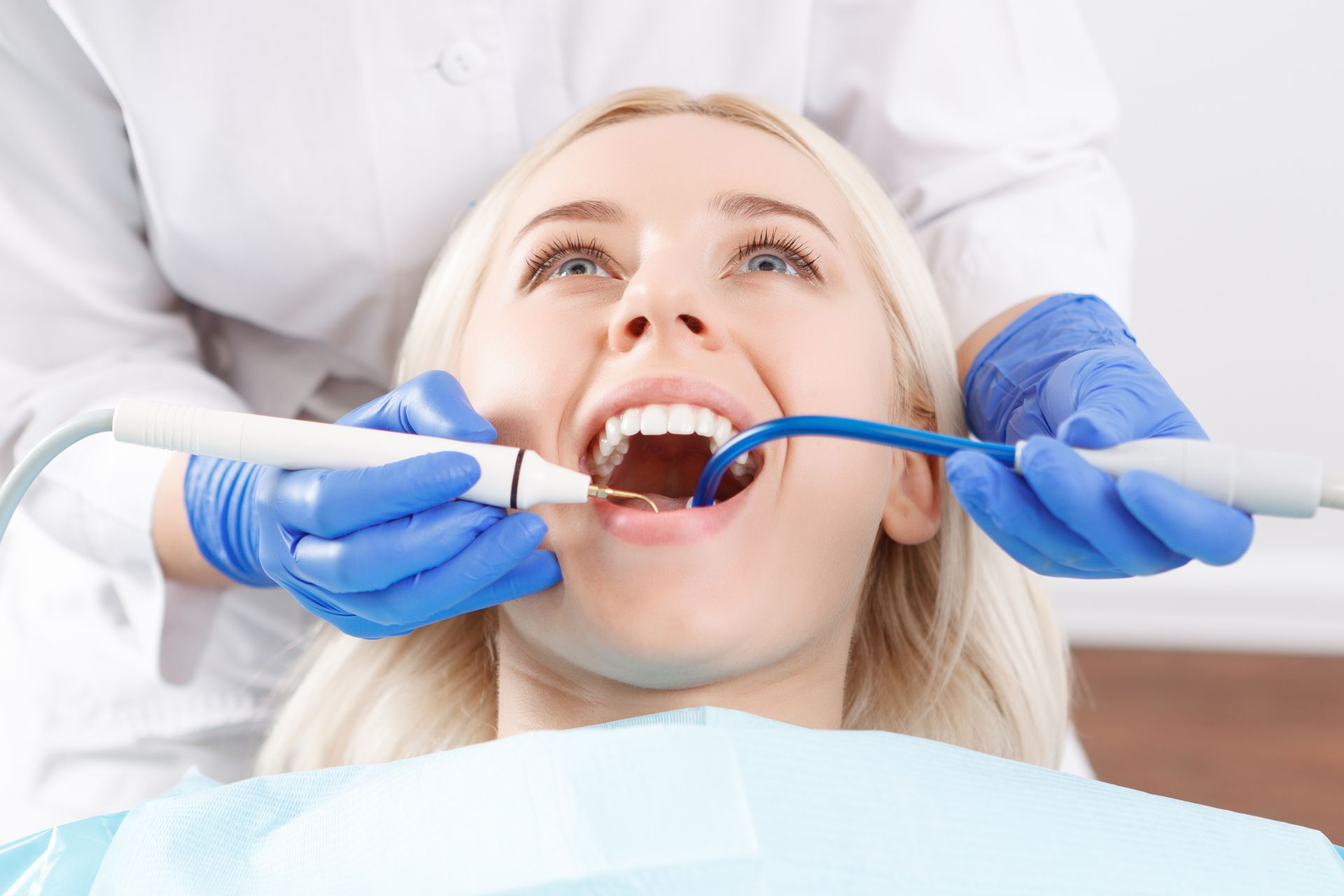 Mains d'une dentiste qui réalise un soin dentaire.