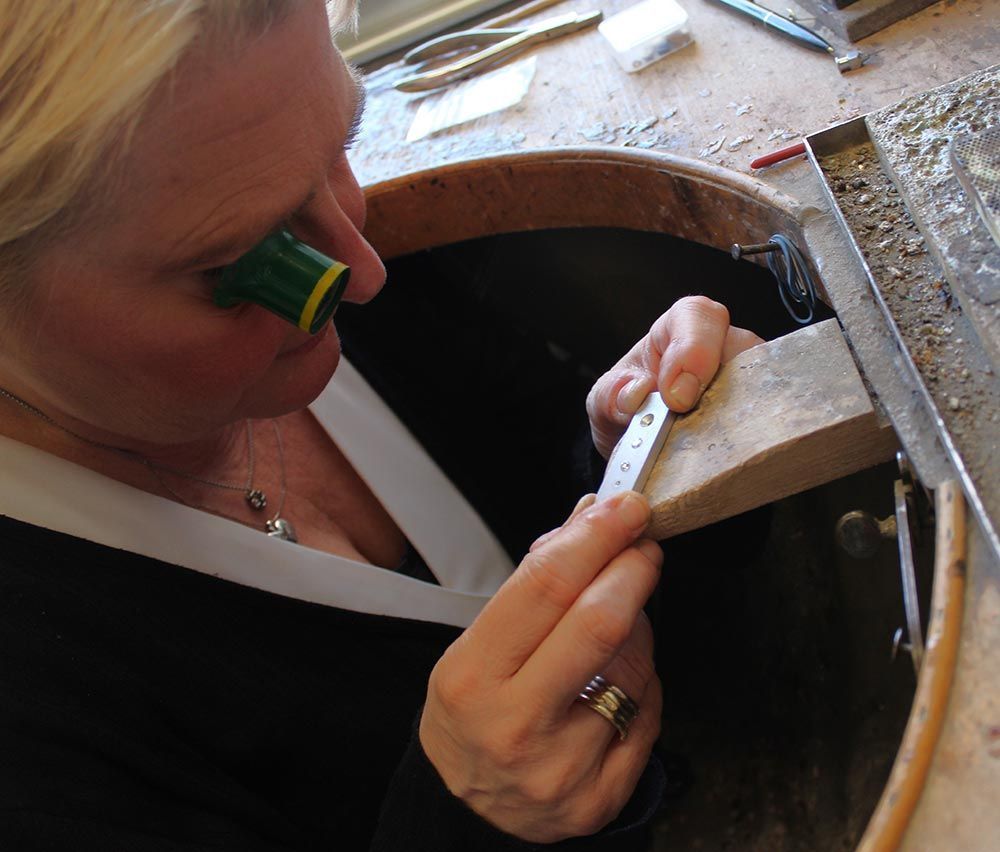 Eine Frau, die einen Ring trägt, arbeitet an einem Schmuckstück