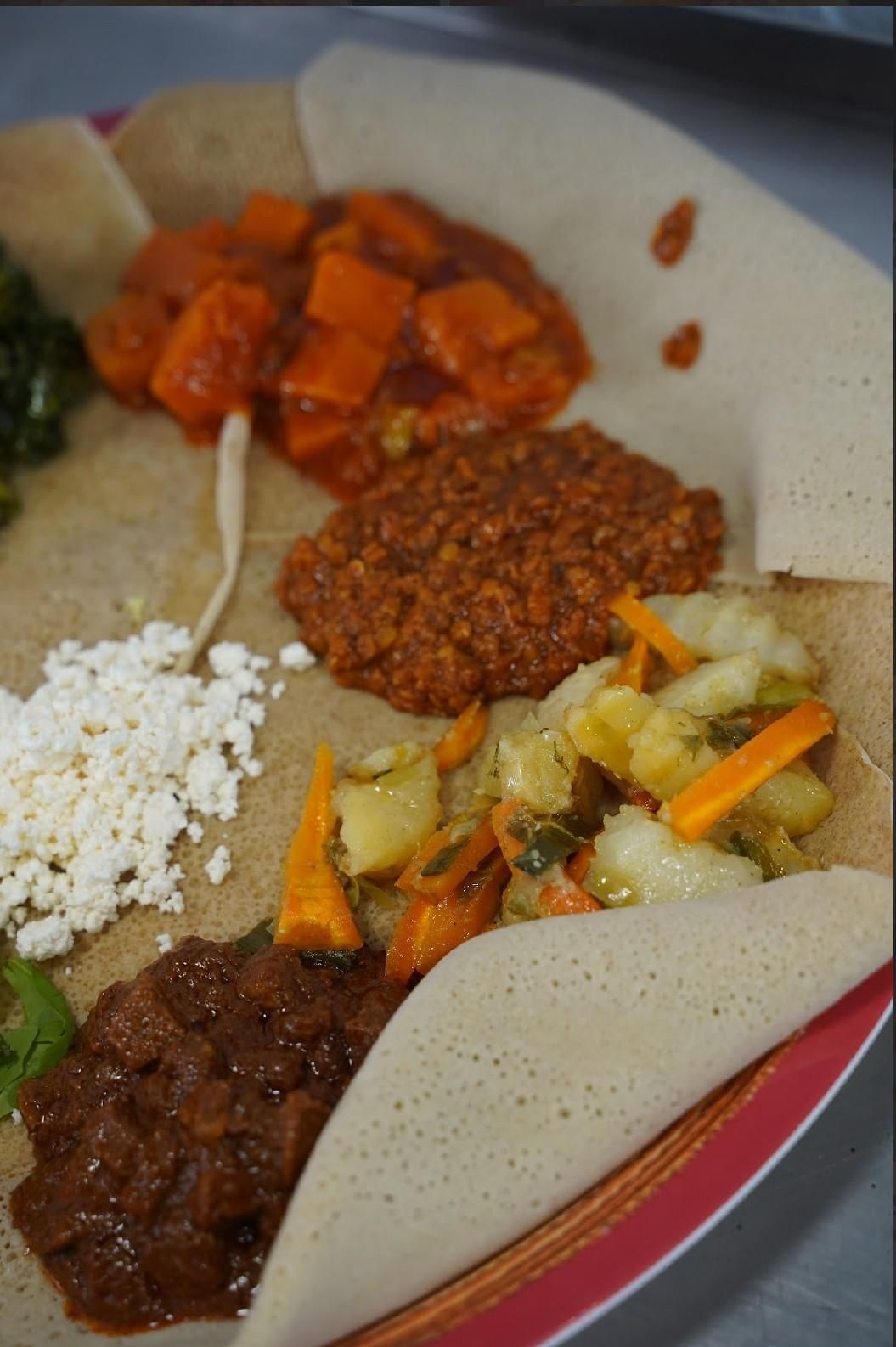 Plato vegetariano etíope en pan injera, con diversos guisos y verduras coloridos.