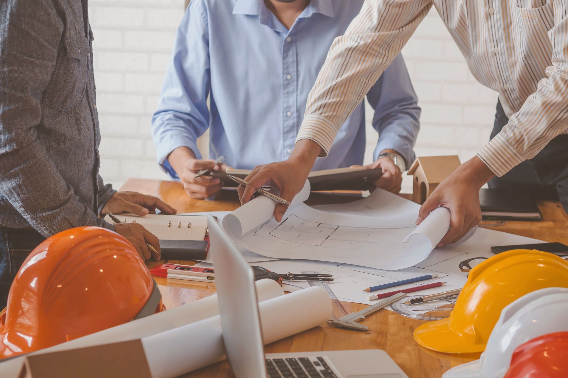 Une équipe de construction, coiffée de casques orange, examine des plans sur une table.