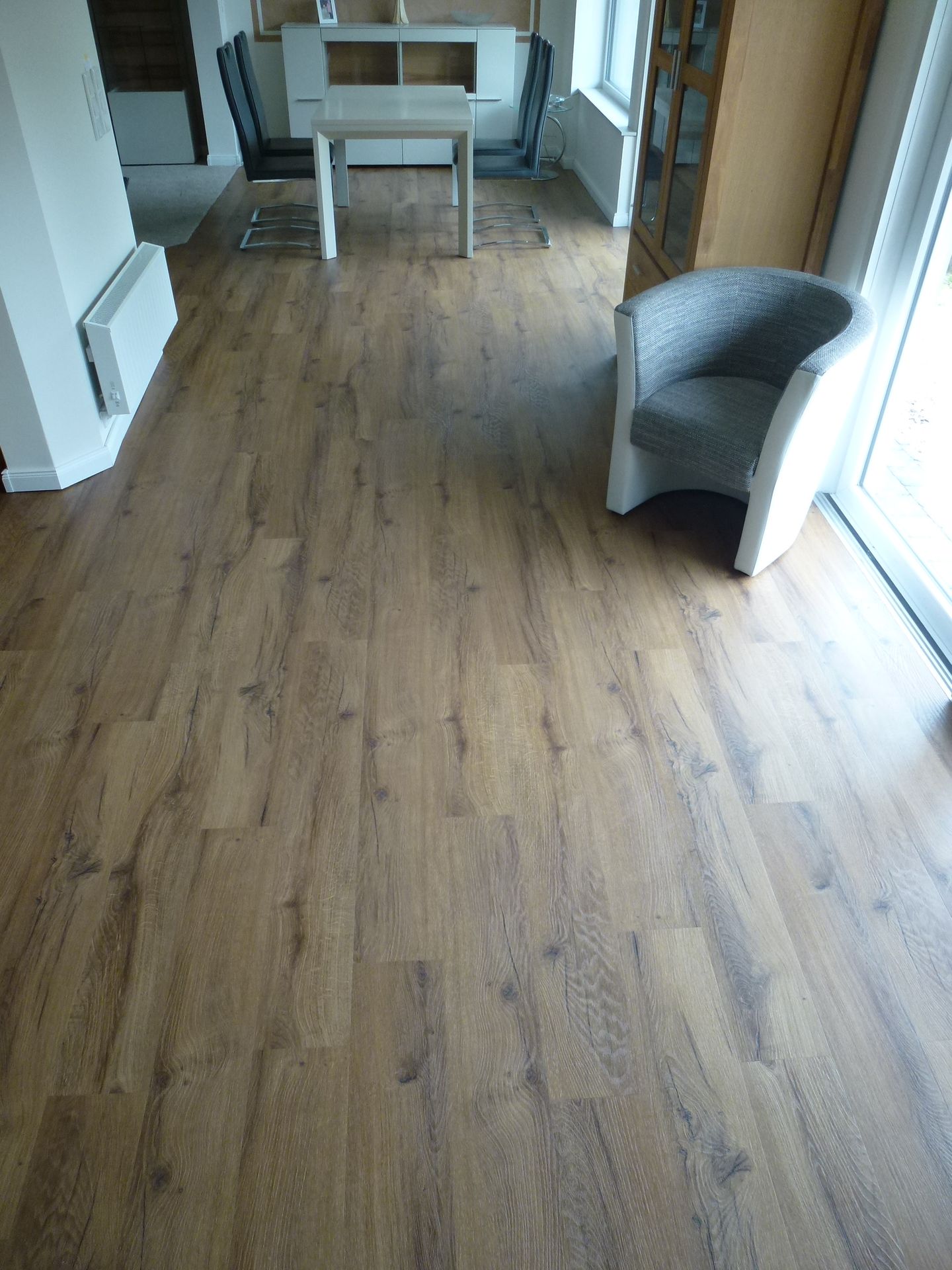 Ein Wohnzimmer mit Holzboden, Tisch und Stühlen.