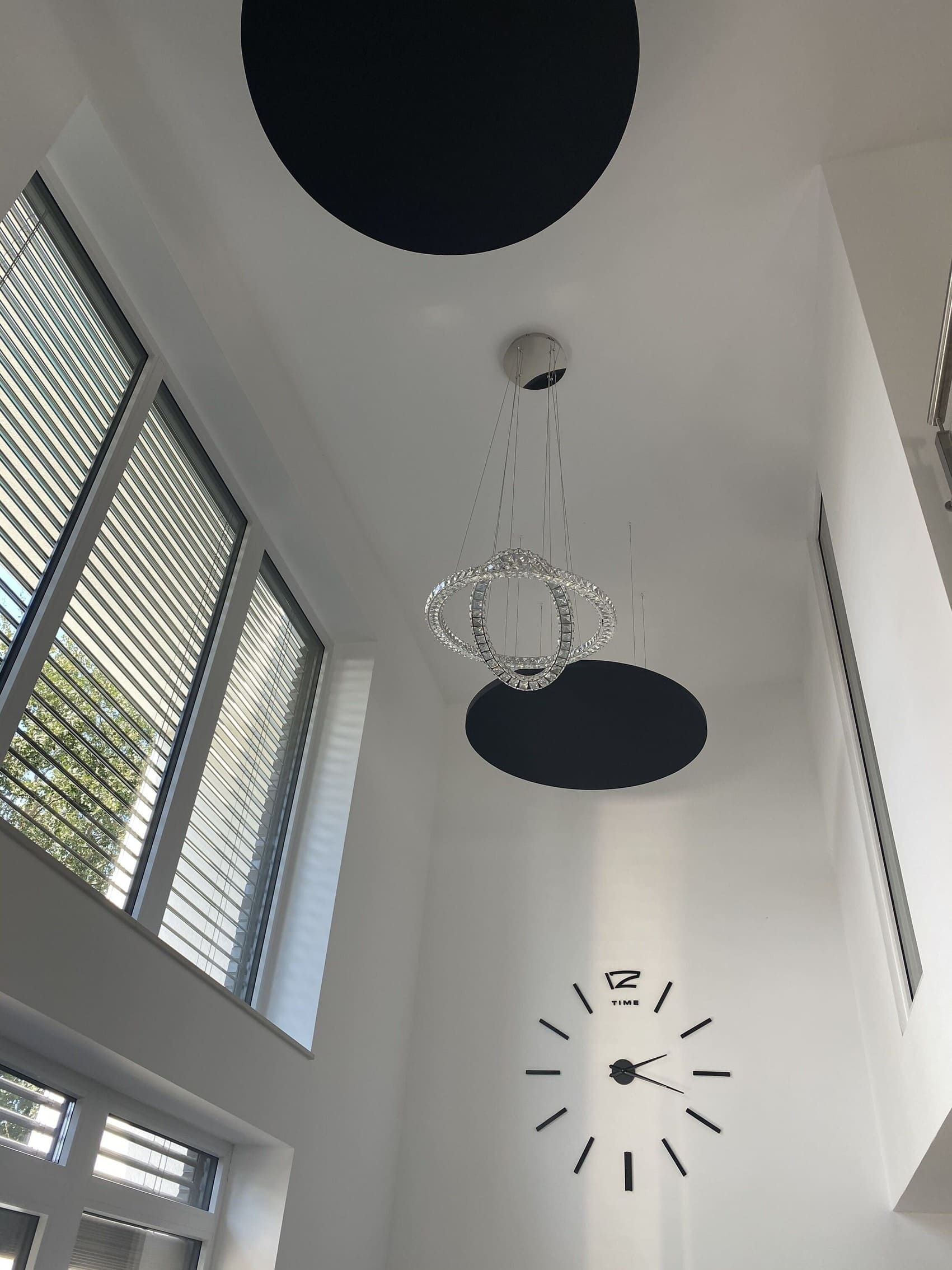 Ein Raum mit einer Uhr an der Wand und einem Kronleuchter, der von der Decke hängt