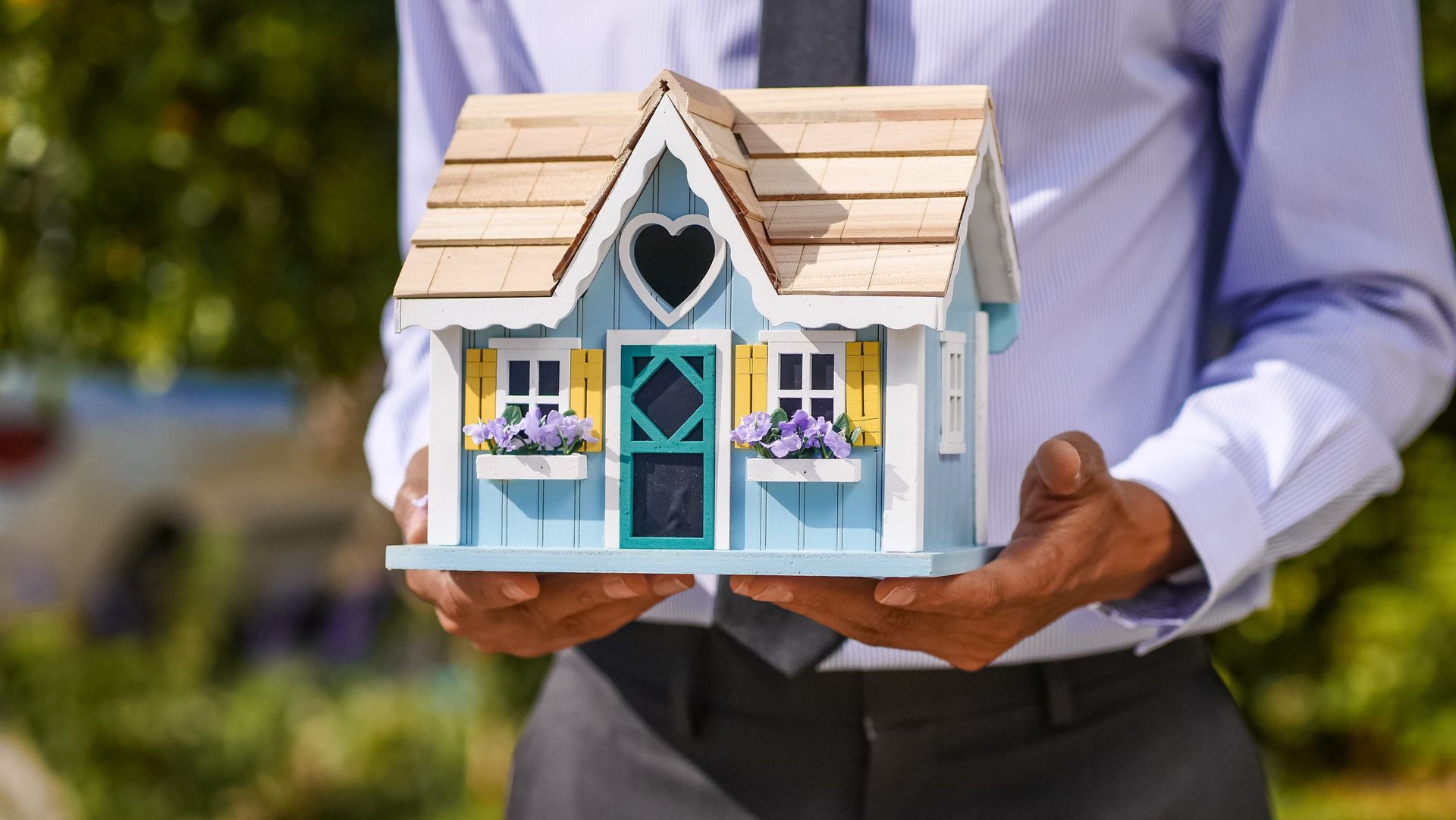Un hombre sostiene en sus manos una pequeña maqueta de casa.