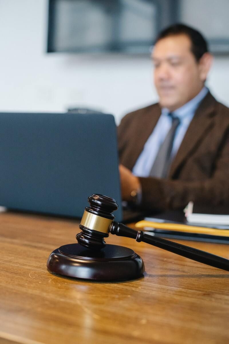 El mazo de un juez está sobre una mesa de madera frente a una computadora portátil.