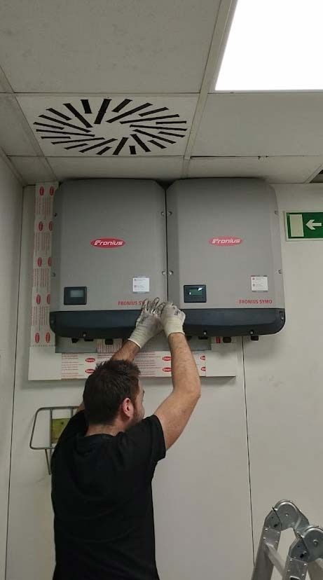 Un hombre está instalando dos paneles solares en una pared.