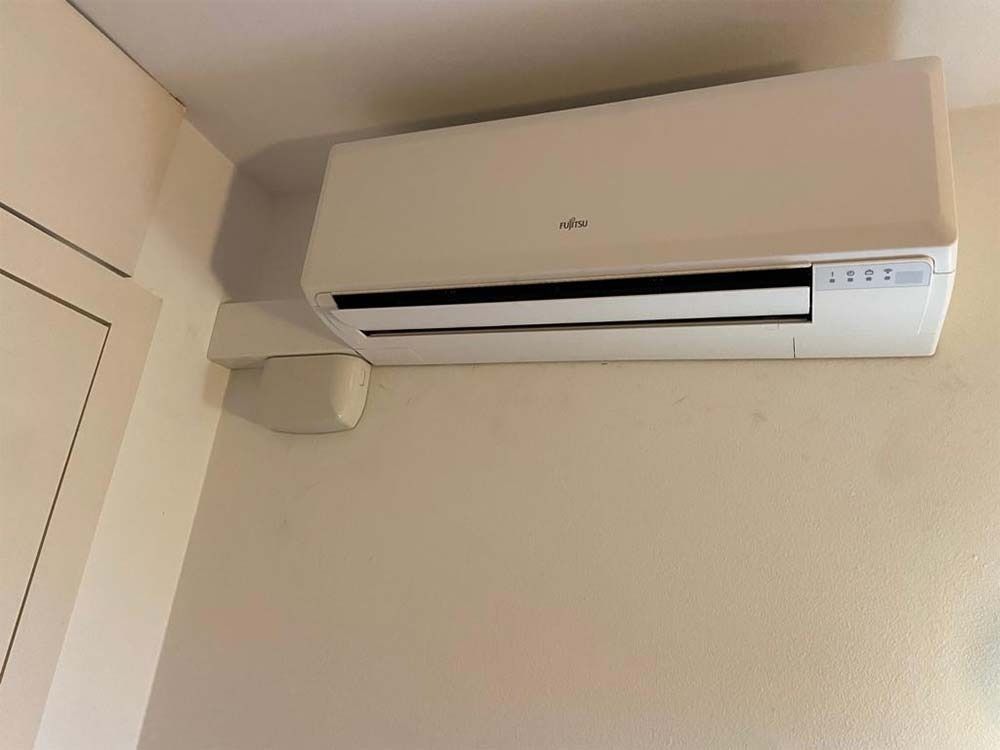 Un acondicionador de aire blanco está colgado en la pared de una habitación.