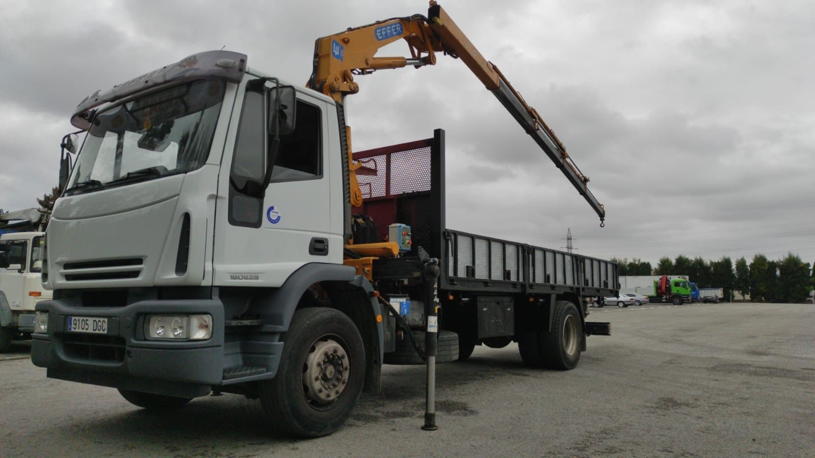 Un camión con una grúa en la parte trasera está estacionado en un estacionamiento