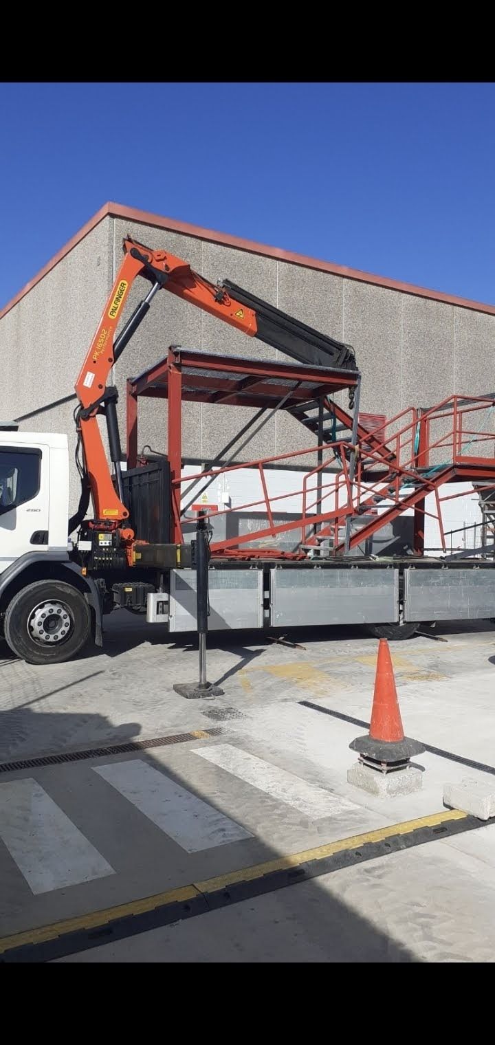 Un camión con una grúa acoplada está estacionado delante de un edificio.