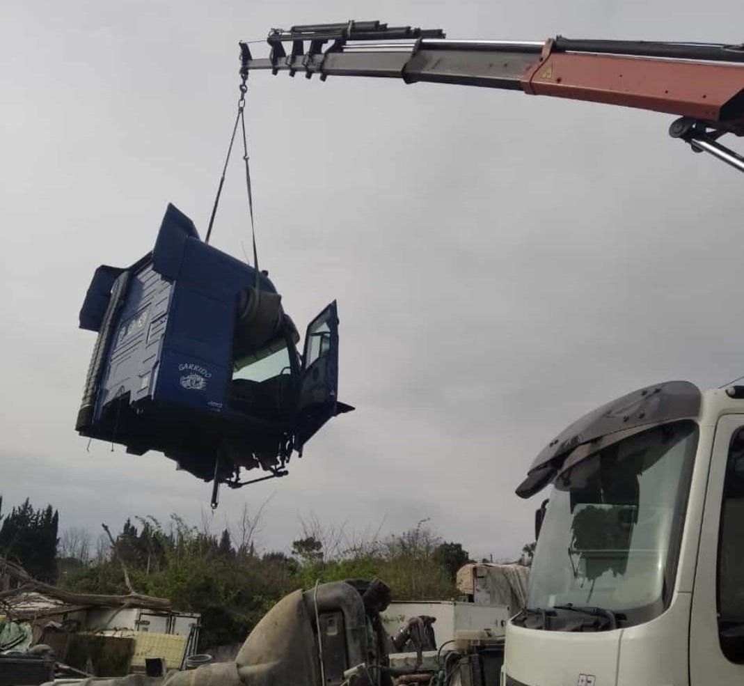 Una grúa está levantando un coche azul en el aire.