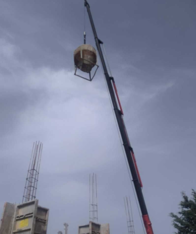 Una grúa levanta un cubo grande en un sitio de construcción.
