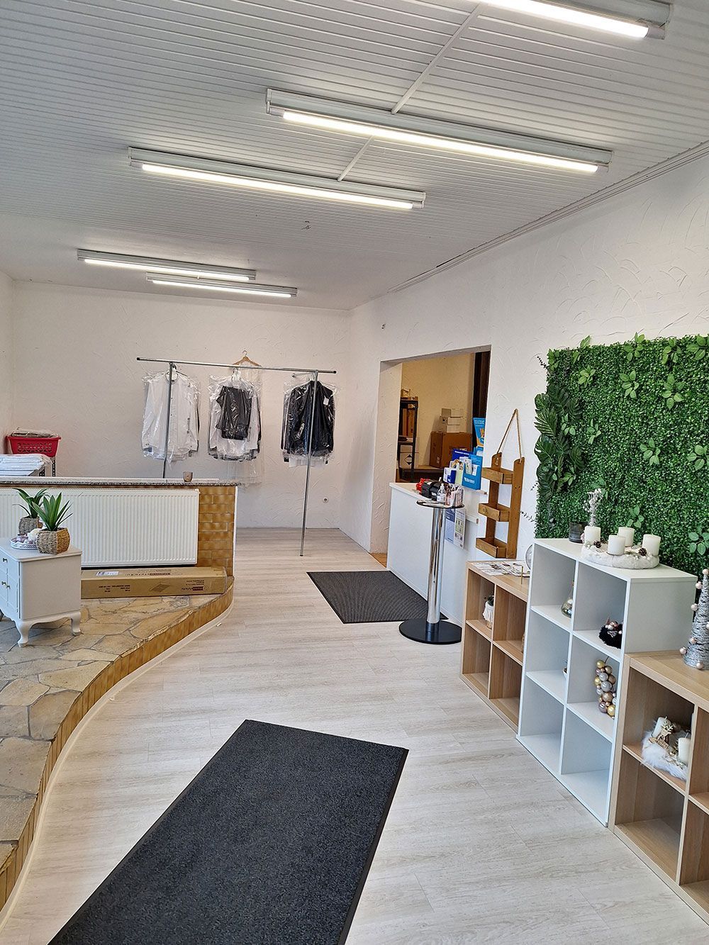 Ein großer Raum mit vielen Regalen und auf Kleiderstangen hängenden Kleidern.