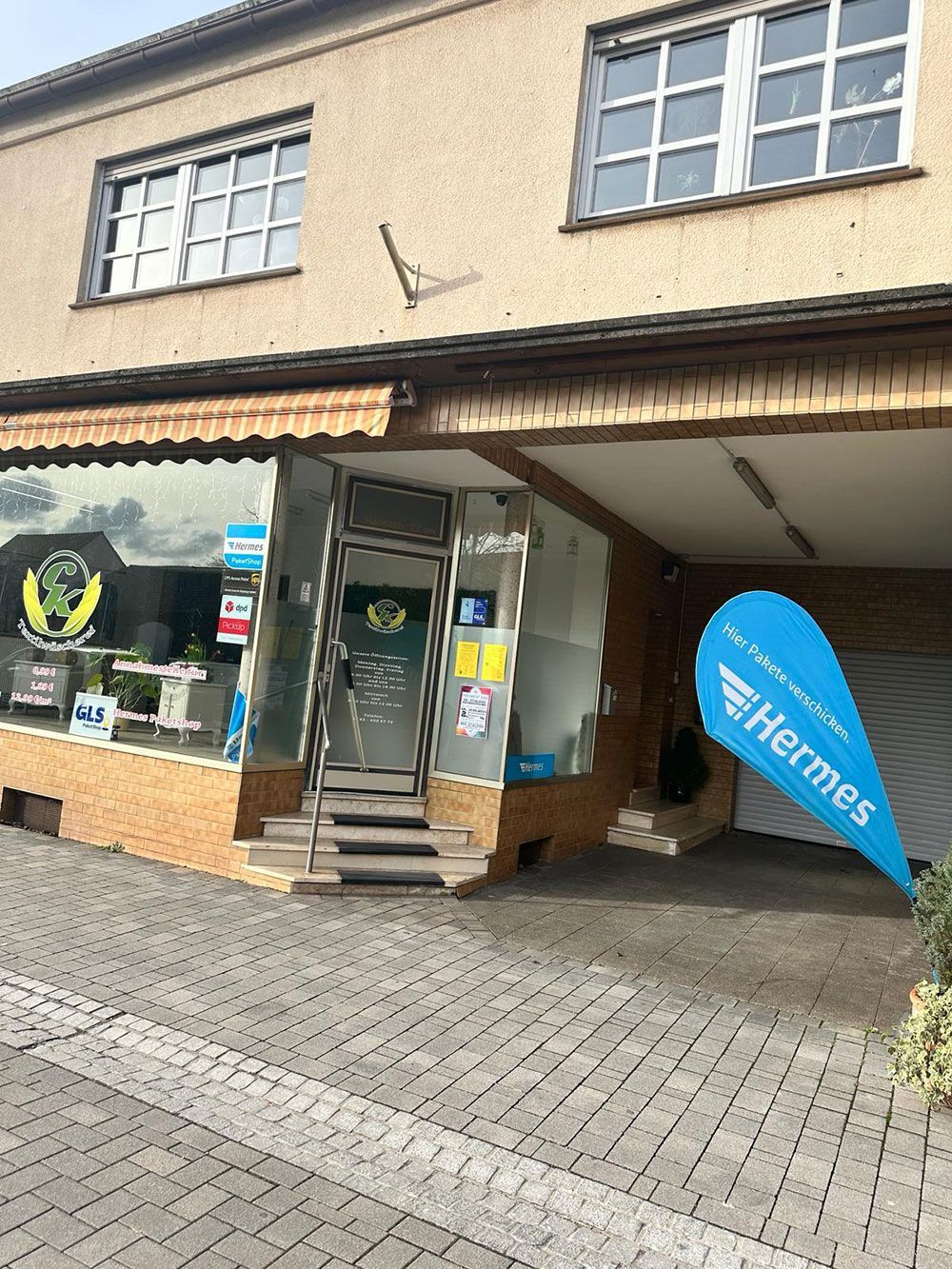 Eine Ladenfront mit einer blauen Flagge, auf der Hermes steht.