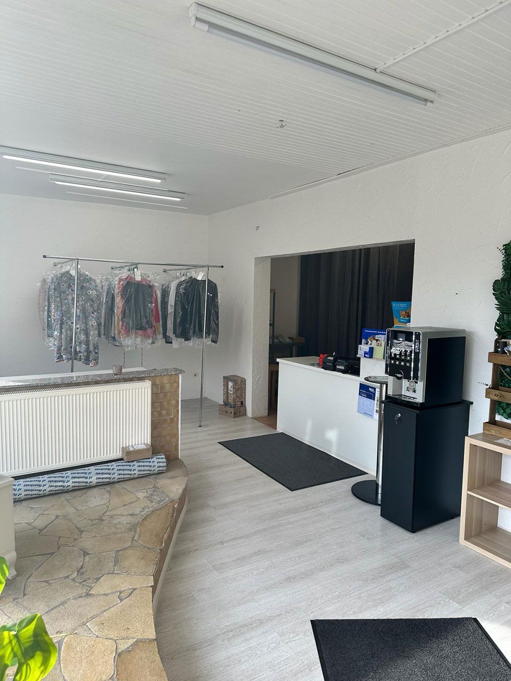 Ein Raum mit auf Kleiderständern hängenden Kleidern und einer Theke.