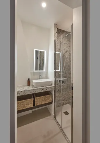 Salle de bains moderne avec lavabo, douche et paniers de rangement. 