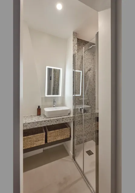 Salle de bains moderne avec lavabo, douche et paniers de rangement.