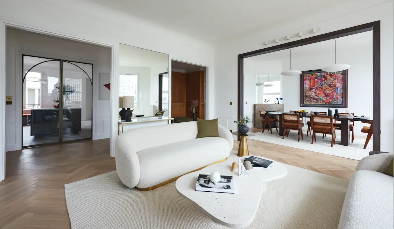 Salon moderne avec canapé blanc, table basse et coin repas. 