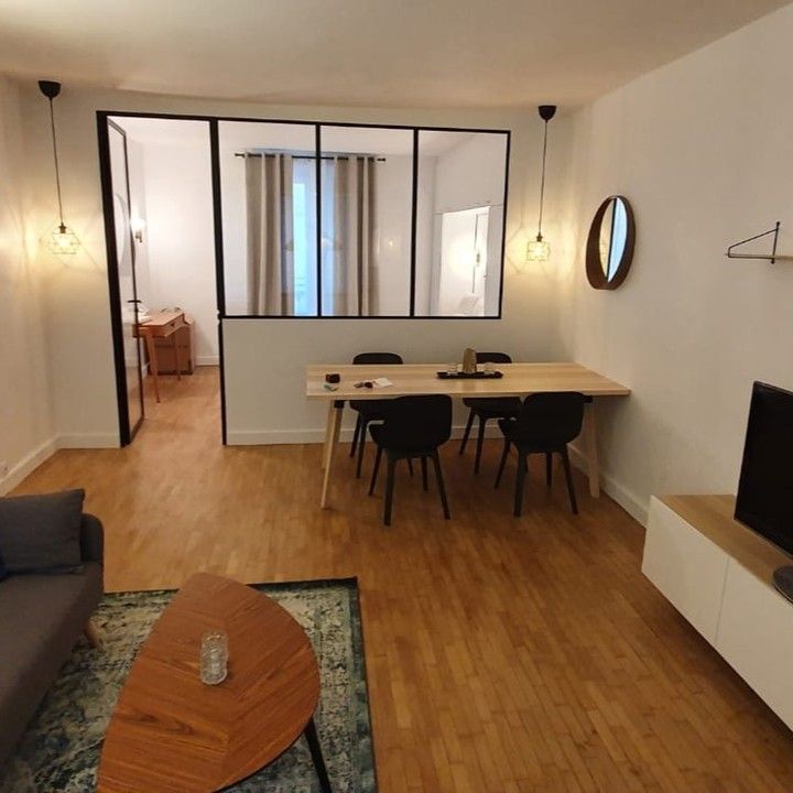 Salon avec coin repas, parquet, chaises et table basse ronde.