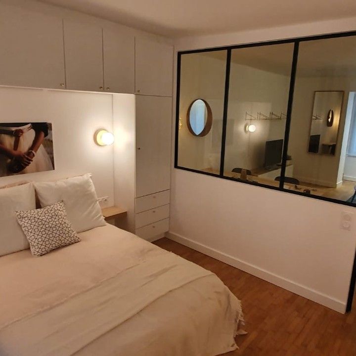 Chambre avec un lit, des rangements intégrés donnant sur une autre pièce.