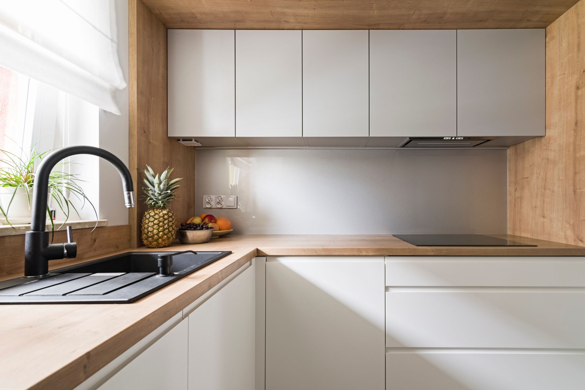 Cuisine moderne avec des touches de bois clair et des armoires blanches. Robinet et évier noirs.