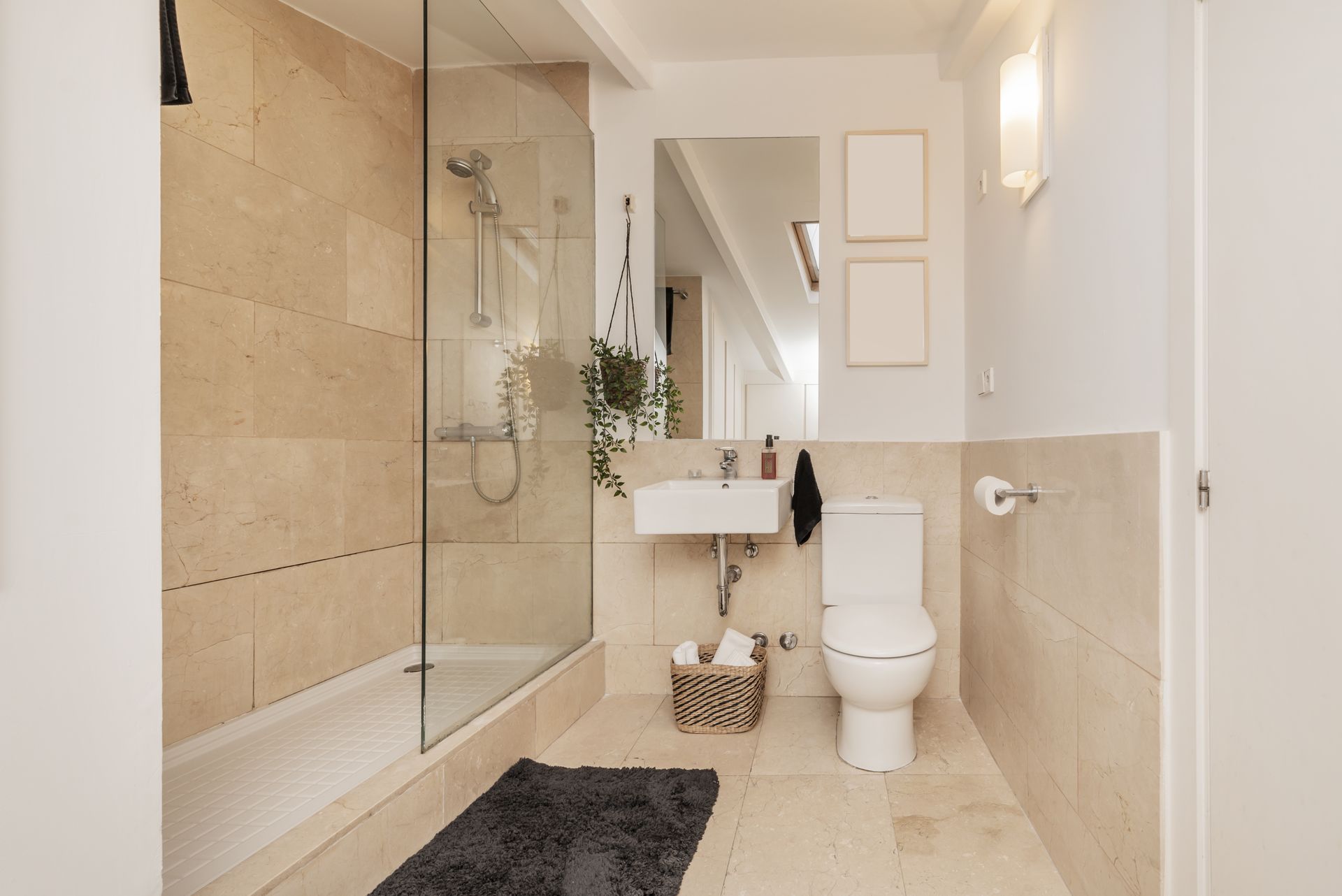 Salle de bains avec carrelage beige, douche en verre, toilettes et lavabo