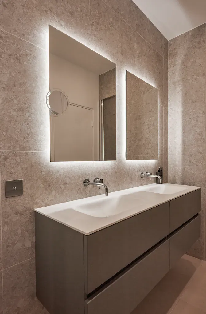 Salle de bains avec meuble double vasque et deux miroirs rétroéclairés.